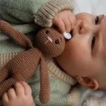 Bébé couché portant sa peluche