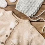 Bannière comportant un cardigan rose avec des oiseaux, un bonnet, une tétine et des chaussettes