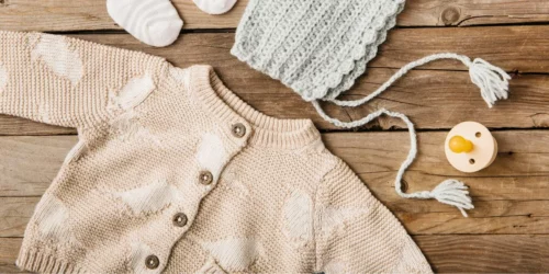 Bannière comportant un cardigan rose avec des oiseaux, un bonnet, une tétine et des chaussettes